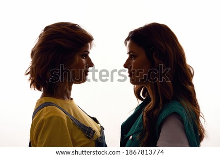 Silhouetted portrait of two young girls, twin sisters in casual wear looking at each other, posing together standing face to face isolated over white background. Family relationships. Horizontal shot ストックフォト © 