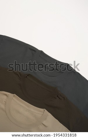 Close up of three basic multicolored shirts on grey background. Casual clothes and fashion concept Stock foto © 