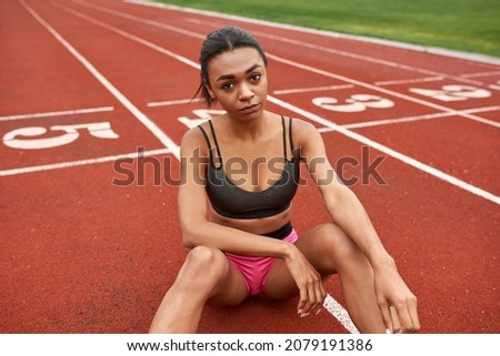 Image, Stock Photo Serious black sportswoman sitting on stone border in city