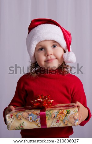 Joyful baby with Christmas gift in Santa\'s hat. Getting ready to decorate a Christmas tree. Christmas, New Year