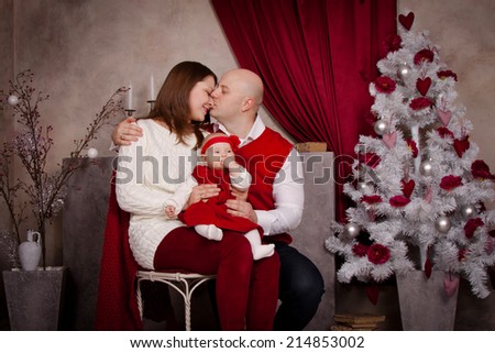 Happy family in santa hat near Christmas tree. Dad hugging and kissing his mother, waiting Christmas miracle, New Year