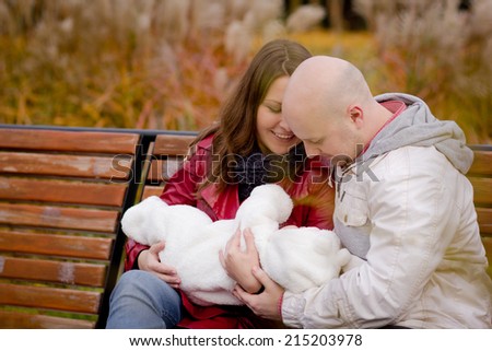 Happy family on a walk in the park. Dad, mom and baby are happy autumn weather and communication. Relax on a bench in the park