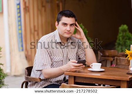 The young man with the phone in a cafe, technology firmly in our lives