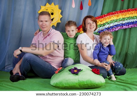Beautiful family on the lawn on a bright rainbow background with clouds and sun