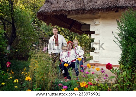 Ukrainian family in national clothes near ethnic house, Ukraine, open-air museum Pirogovo