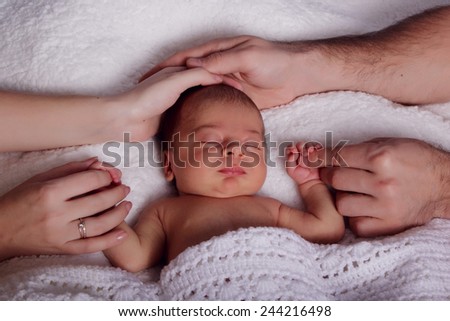 Hands of mom and dad closeup embracing sleeping newborn