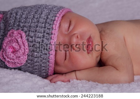 Beautiful sleeping newborn baby in knitted cap under the rug