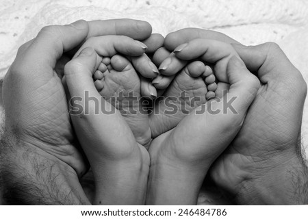 Legs newborn baby hands hug mom and dad, forming a heart. Symbolizes love, unity, caring, tender to the baby