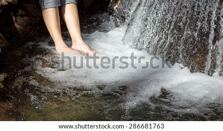 hiker washing her feet in a waterfall