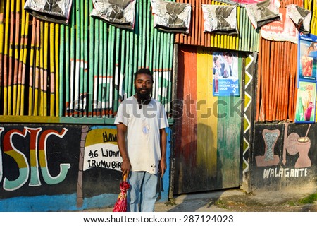 Livingston, Guatemala - March 7, 2015: Garifuna rasta man poses while holding an umbrella in one hand and a machete handle in the other on March 7, 2015 in Livingston, Guatemala.