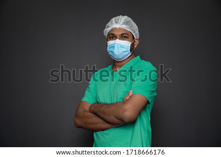 Portrait of a male nurse standing with arms folded isolated on a black background. Asian Nurse looking at camera. Male nurse with protective face mask against corona virus epidemic COVID-19
