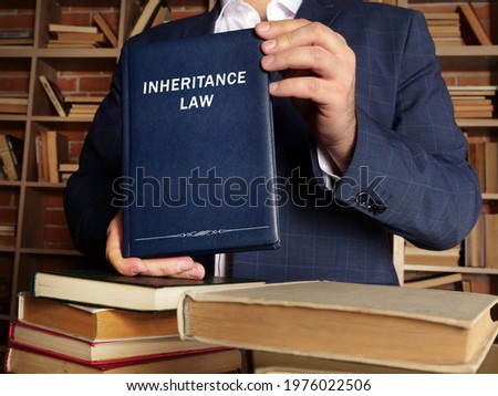  INHERITANCE LAW book in the hands of a lawyer. Inheritance law governs the rights of a decedent's survivors to inherit property. Imagine de stoc © 