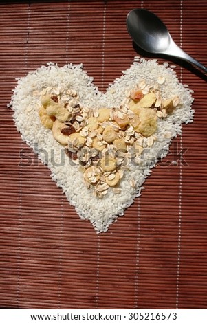 Rice and muesli laid out in a heart shape on bamboo napkin with a spoon. Healthy food.