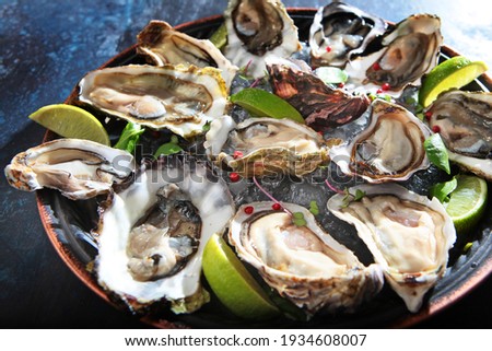Fresh oysters with lime on a round plate. Oyster season. Macro-seafood dish. Oyster on the half shell.Two varieties of oysters.Out of focus.