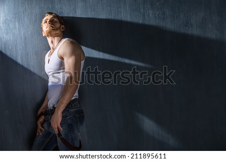 attractive man in shirt standing near the wall in the studio. lighting point light
