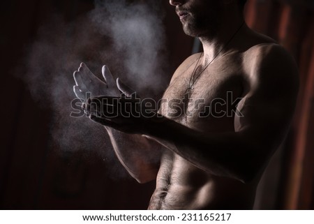 cropped view of a male gymnast dusting his hands with chalk