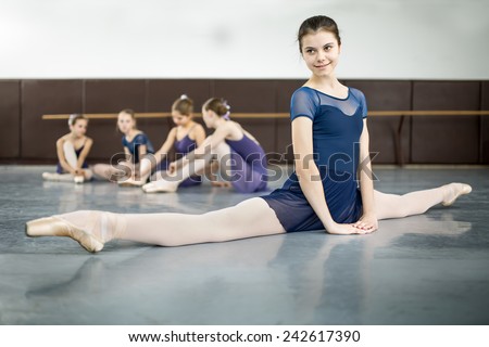 ballerina sitting on the floor in the splits in a dance class dancers practicing on the background