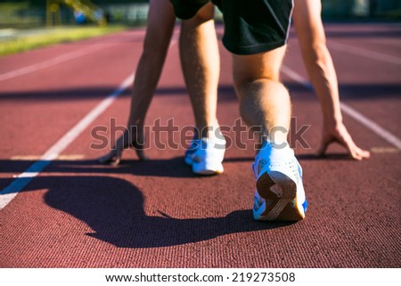 Sport man running. Runner sprinting training for marathon. Young strong male fitness model during run outdoors in stadium.