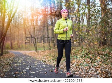 Runner woman training in city park outdoor. Caucasian female sport fitness model jogging training for marathon during autumn outdoor workout.