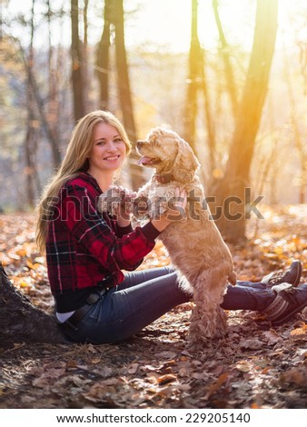 Young beautiful woman and her dog (American Cocker Spaniel) posing outside at fall time