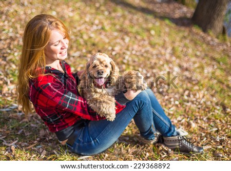 Young beautiful woman and her dog (American Cocker Spaniel) posing outside at fall time