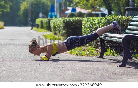 Fitness woman doing push-ups during outdoor cross training workout. Beautiful young and fit fitness sport model training outside.