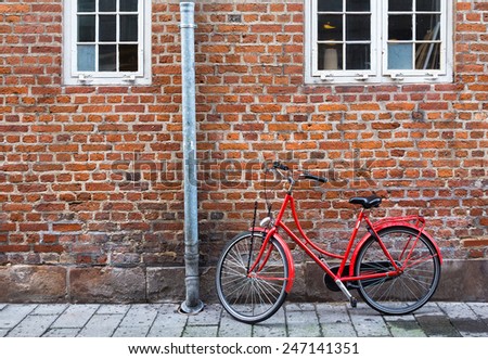 Red bicycle near red wall in Copenhagen, Denmark