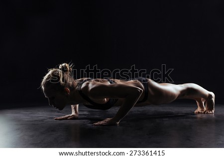 Sport woman doing push-ups on black background