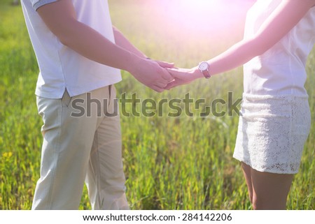 Happy couple holding hands in summer day in the sunset