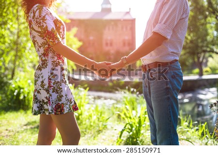 Young couple in love holding hands in the sunset in summer evening. Bright toning picture