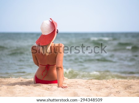 Young woman in red hat relax on beach in the sea in sunny hot day