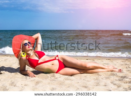 Young woman in red hat and sunglasses relax on beach in the sea in sunny hot day