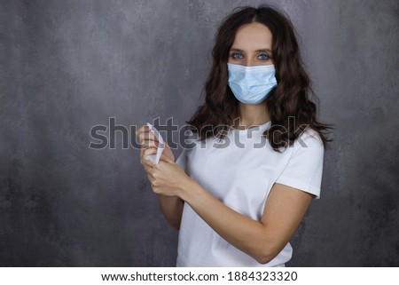 A young attractive girl in a medical mask treats her hands with a salette Photo stock © 