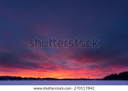 Vibrant and colorful sunset over frozen lake during Winter in Stockholm, Sweden