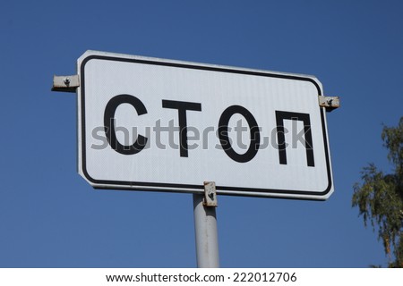 A black and white road sign STOP closeup on the background of pure blue sky on a sunny day in Russia