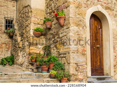 Corner in a Tuscany town with a lot of flowers and plants, just near a door entrance