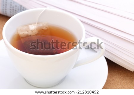 white cup of tea with newspaper rolled reading in the morning outdoor area for refreshment