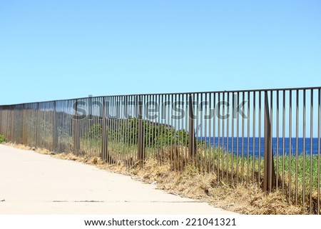 structure design iron fencing on footpath near water bay with blue sky background