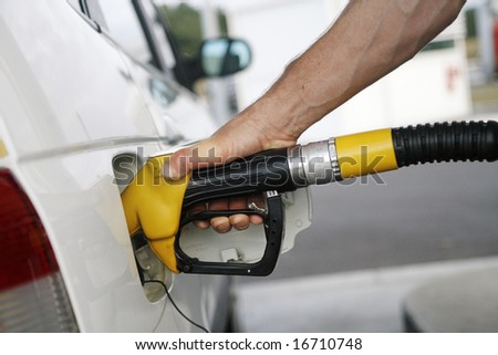 man\'s hand refilling the car with a gas pump