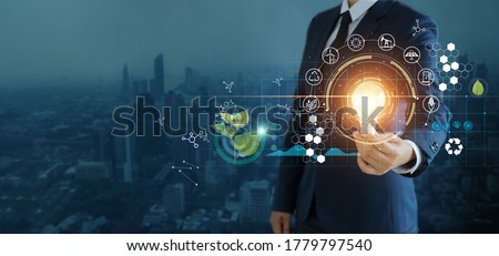 businessman holding light bulb against nature on city background  with icons energy sources for renewable, sustainable development,  Ecology and renewable energy concept.
