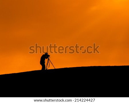 Silhouette shot of a photographer taking a photo over the hill