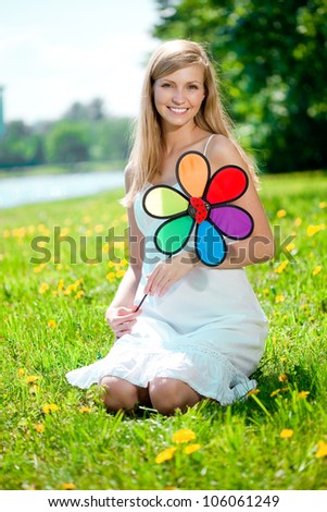 Beautiful smiling woman with a rainbow flower outdoors