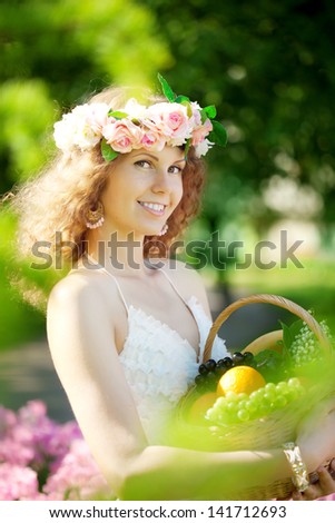 Cute young woman with a basket of fruit in hand