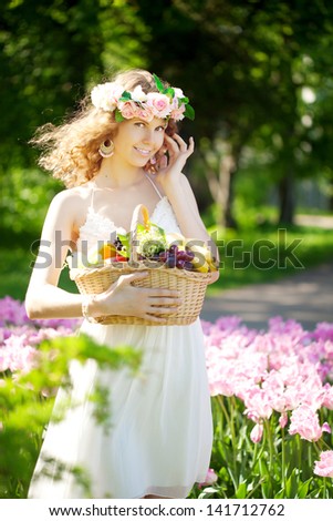 Cute young woman with a basket of fruit in hand