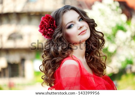 Beautiful woman in a bright red dress on a background of the mill