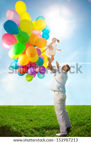 Father throws daughter. Family playing together in park with balloons. Father tosses a baby against the sky