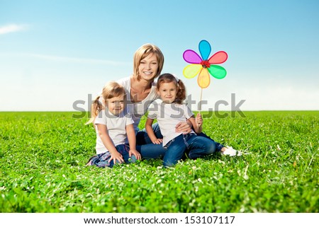 Happy family in outdoor park  at sunny day. Mom and two daughters in the green garden.  Group of people on green grass.