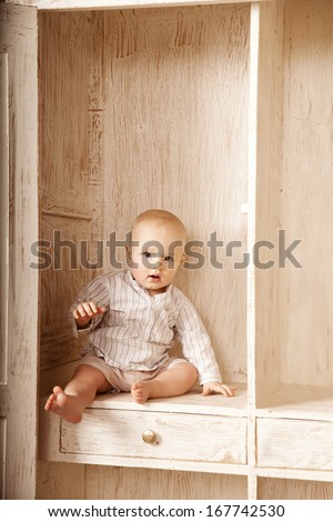 Beauty little baby sitting in the closet. Smiling child and interior of a bedroom. Cute kid