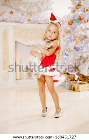 Beauty little Santa girl near the Christmas tree.  Happy girl with bunny celebrates  christmas.