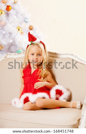 Beauty little Santa girl near the Christmas tree.  Happy girl celebrates  christmas.